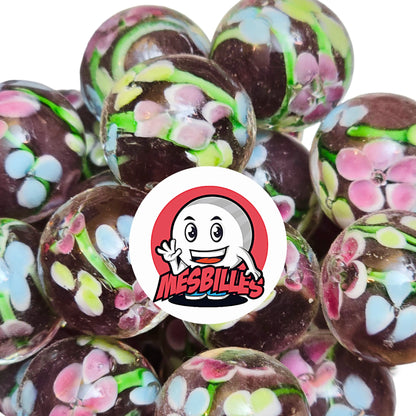 La Bille Art Tige Fleurie Violette 16 mm est une merveille soufflée à la main où s’épanouissent de délicates fleurs colorées : bleu tendre, rose poudré et jaune pastel.